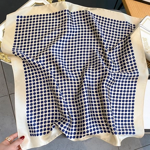 Elegant mulberry silk polka dot square scarf in cream and navy blue displayed on a tray