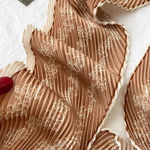 Detailed macro view of caramel floral pleated scarf texture with delicate wavy edges