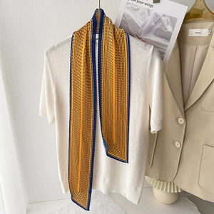 Dettaglio di un foulard plissettato a righe gialle e blu su un top in maglia bianca