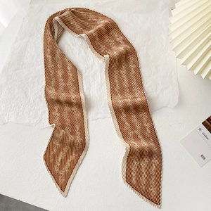Macro detail of brown pleated skinny scarf with white floral print and wavy edges