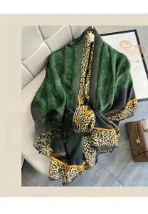 Detail of emerald green shawl with leopard print trim and floral pattern on chiffon fabric