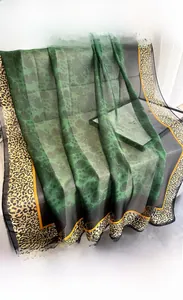 Close-up of lightweight emerald floral scarf with yellow leopard print border on a grey sofa