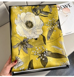 Detailed texture of yellow silk scarf with white floral and butterfly patterns
