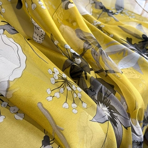 Close-up of lightweight yellow floral chiffon fabric with elegant draped texture