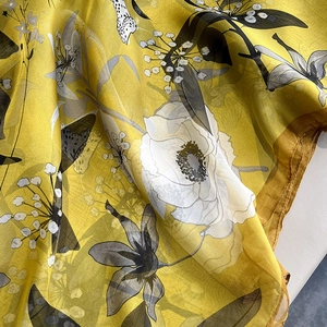 Detail of yellow floral silk scarf fabric showing lightweight chiffon texture and print