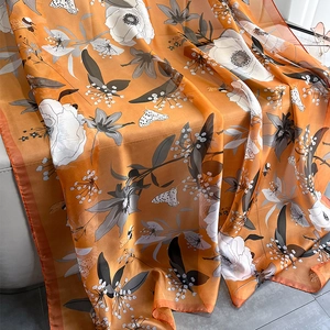 Detail showing sheer orange floral shawl with white flower prints and butterfly patterns