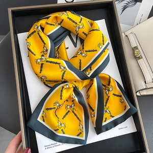 Elegant yellow silk scarf with horse print and green border on black tray display