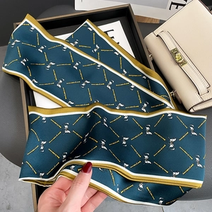 Close-up of dark green silk twilly with gold horse chain pattern on a leather handbag
