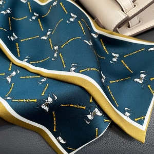 Detail of silk scarf with vintage horse print and gold buckles on a leather bag