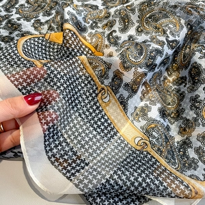 Detail of sheer paisley scarf showing lightweight texture and elegant gold chain pattern