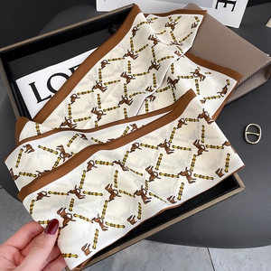 Detail of silk scarf featuring classic horse patterns and gold chain motifs in earthy tones