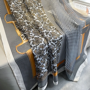 Detail of silk scarf with houndstooth and paisley patterns draped on a white sofa
