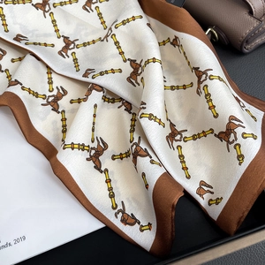 Detail of vintage horse print silk scarf with equestrian patterns on a brown leather bag