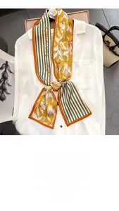 Détail d'un foulard étroit imprimé à fleurs et rayures sur une chemise blanche