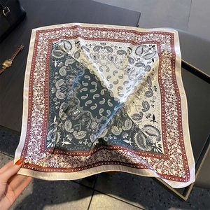 Dettaglio ravvicinato di foulard in seta paisley con bordi geometrici bordeaux e verdi