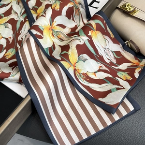 Détail d'un foulard en soie à fleurs et rayures drapé sur un sac à main de luxe