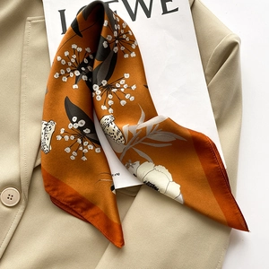 Detail of silk scarf showing floral and butterfly patterns on a khaki blazer