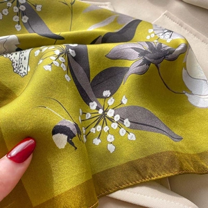 Close-up of silk scarf showing detailed floral prints, bees, and rolled edge texture
