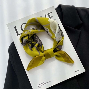 Detailed view of floral silk scarf tied in a bow on a book with a black blazer background