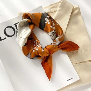Detail of a bright orange silk scarf with white floral patterns tied as a necktie
