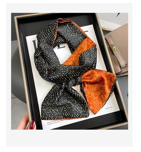 Detail of a double-sided long silk scarf featuring orange floral and black dotted patterns