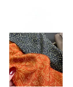 Detail shot of imitation silk fabric showing orange leaf patterns and golden wave textures