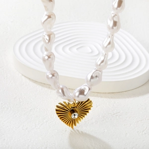 Collier de perles baroques avec pendentif coeur doré et cristal sur un support élégant
