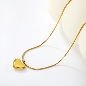 Close-up of minimalist 18K gold heart pendant on a shiny snake bone chain necklace