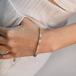 Détail d'un bracelet en acier inoxydable doré 18K avec sertissage de zircons carrés
