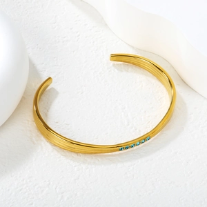 Détail du bracelet ouvert plaqué or 18K avec rainures texturées et cristaux bleu ciel