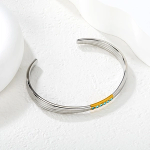 Détail du bracelet ouvert en acier inoxydable bicolore orné de cristaux bleus
