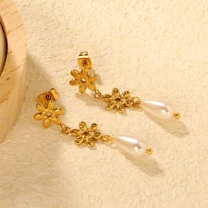 Boucles d'oreilles fleurs dorées avec perles goutte d'eau sur fond texturé minimaliste