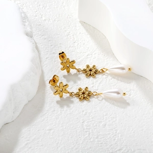 Gold flower earrings with white teardrop pearls and tassels on minimalist white background