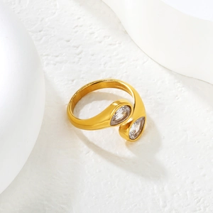 18k gold irregular geometric open ring with pear-cut cubic zirconia on a stone surface