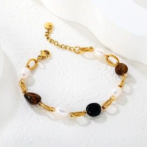 Bracelet doré en acier inoxydable avec oeil de tigre et perles sur socle blanc