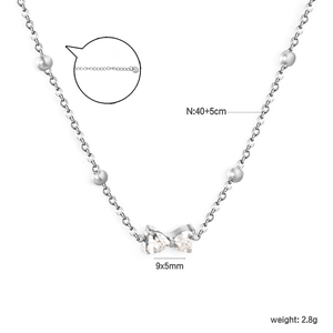 Elegante collar con colgante de lazo plateado, circonitas de corazón y cadena de bolas