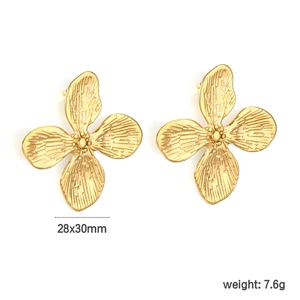 Détail macro de boucles d'oreilles fleur à quatre pétales avec texture en métal brossé