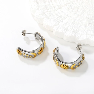 Détail macro de boucles d'oreilles en C argentées avec motifs soleil lune et étoiles