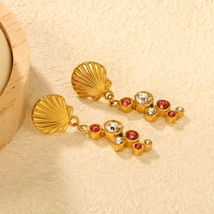 Gros plan de boucles d'oreilles dorées en forme d'éventail avec pierres rouges et claires