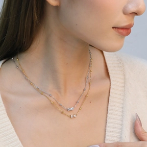 Elegante collar de dos capas con colgantes de lazo en oro y plata en una modelo
