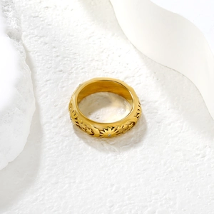 Golden wide band ring with sunflower engravings and zircons on a white rock base