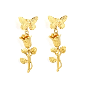 Boucles d'oreilles pendantes papillon et rose dorées avec perles sur fond blanc