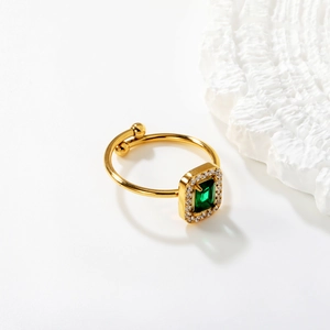 Macro shot of 18K gold open ring with emerald-cut green gemstone and pave zircon details