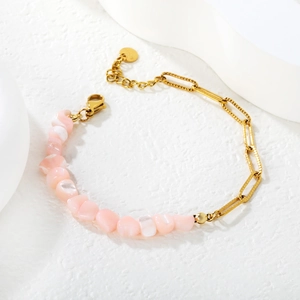 Détail d'un bracelet en perles de coquillage rose et chaîne à trombone dorée