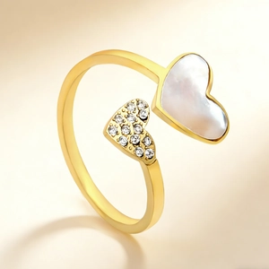 Dettaglio macro di cuore in madreperla e cuore di diamanti su anello dorato regolabile