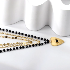 Close-up of three-layer stainless steel gold necklace with heart evil eye and black beads