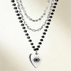 Detail of triple-layer necklace featuring heart pendant and evil eye on black beads