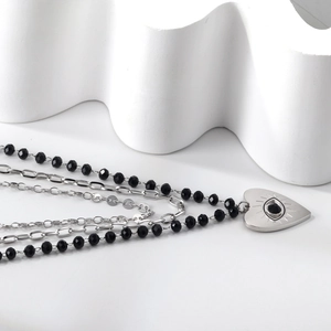 Detailed close-up of triple-layer evil eye heart necklace with black beads and silver finish