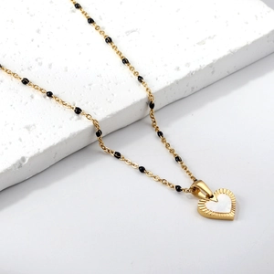 Detail of 18K gold-plated heart pendant necklace with white enamel and black beads