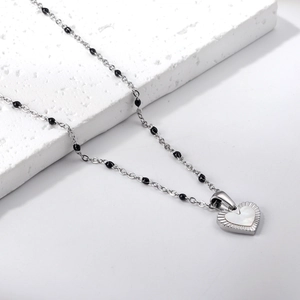 Close-up of heart pendant necklace with black beads and mother-of-pearl inlay detail